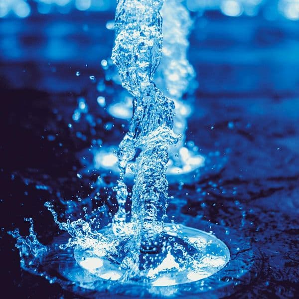 A jet of water splashing on a blue lit surface